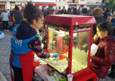 Servidora de palomitas en evento local, con una niña disfrutando de las palomitas.