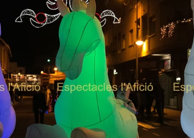 Caballo hinchable verde iluminado en desfile nocturno.