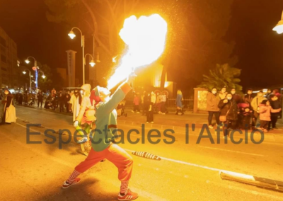 Elfo lanzando fuego en un desfile nocturno.