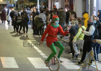 Elfa en monociclo en un desfile navideño.