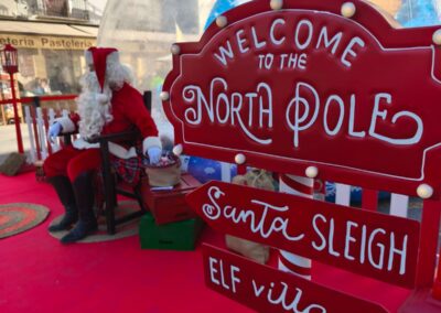 Decoración navideña con un cartel que dice 'Welcome to the North Pole' y Papá Noel al fondo.