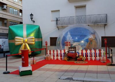 Decoración navideña con una esfera gigante, un regalo inflable y un buzón rojo.