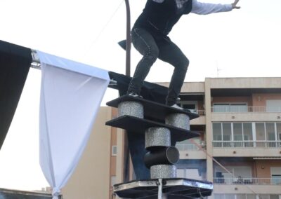 Artista equilibrándose sobre una estructura en un espectáculo al aire libre.