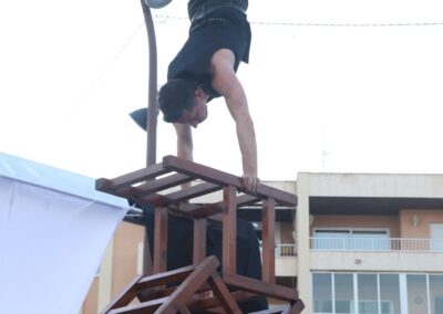 Artista haciendo el pino sobre una pila de sillas.