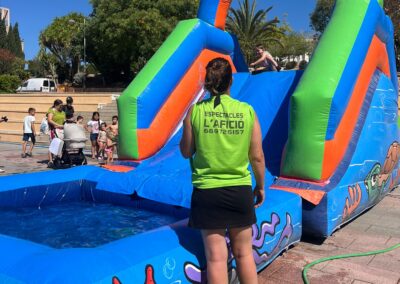 Monitora supervisando un tobogán acuático hinchable con piscina.