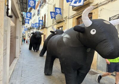 Toros hinchables en un encierro infantil por una calle decorada.