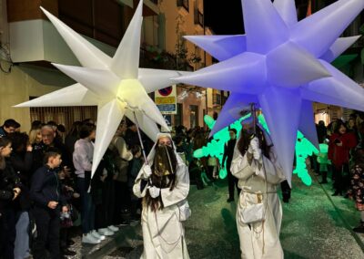 Personas con estrellas hinchables luminosas en un desfile nocturno.