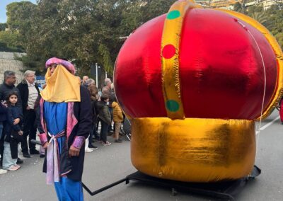 Corona hinchable roja y dorada en desfile al aire libre.