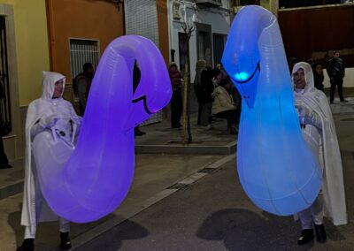 Participantes con figuras hinchables luminosas en un desfile nocturno.