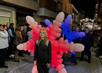 Persona junto a figura hinchable luminosa en un desfile nocturno.